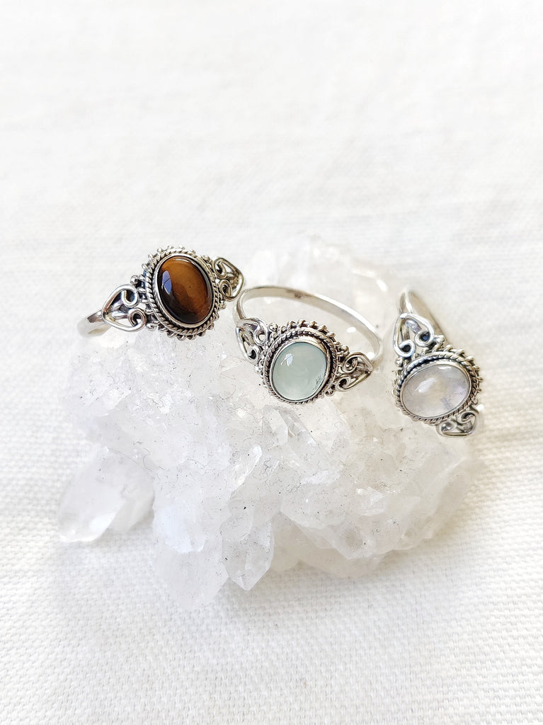 This is three sterling silver rings with an oval crystal gemstone. One has a tigers eye gemstone brown in colour, one has a chalcedony gemstone light blue in colour and one has a moonstone gemstone rainbow white in colour, all are available at our third eye crystal and jewellery store in Auckland, New Zealand