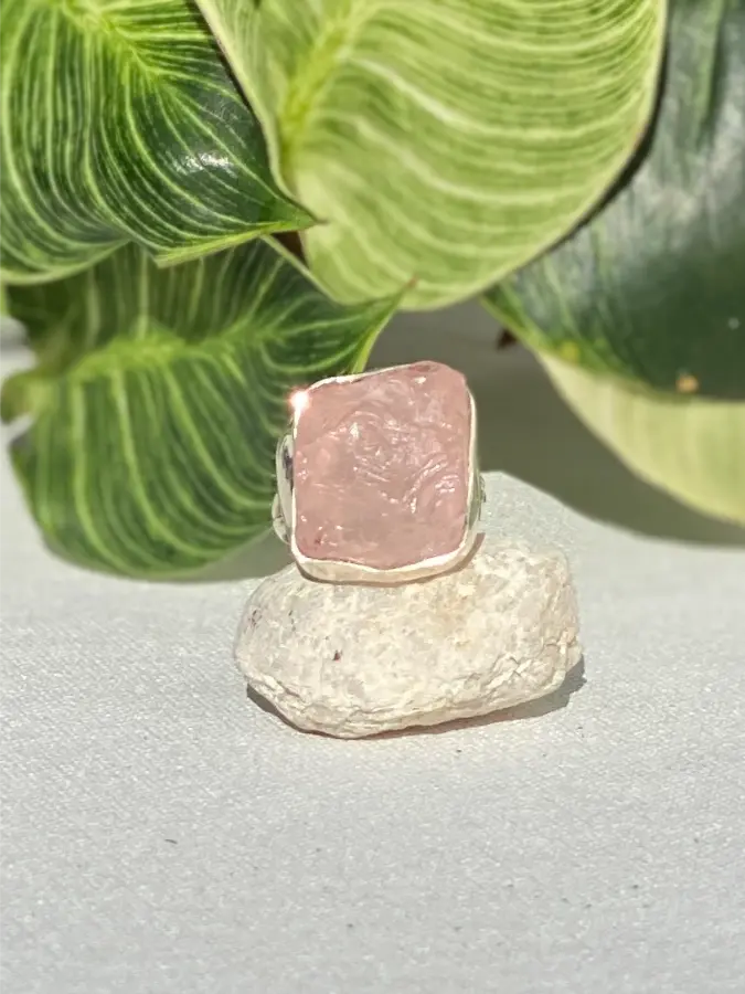 Ring with a pink Rose Quartz, set in Sterling Silver.  Stone on a rock with green leaves in the background