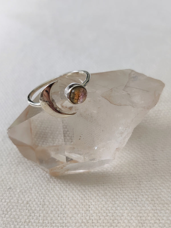 This is a sterling silver ring with a crescent moon and labradorite stone that is light rainbow grey in colour, sitting on top of a clear quartz crystal, that are both from our third eye crystal and jewellery store in Auckland New Zealand