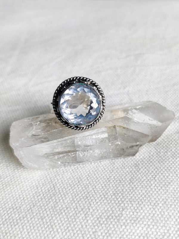 This is a sterling silver bezel set and detailed rose quartz ring sitting on top of a clear quartz crystal, both available at our third eye crystal and jewellery store in Auckland, New Zealand