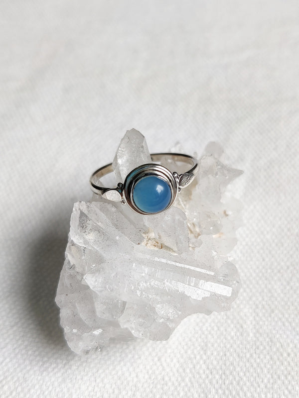 This is a sterling silver ring with a simple design and chalcedony crystal gemstone that is light blue in colour, sitting on top of a clear quartz crystal, both available at our third eye crystal store in Auckland New Zealand