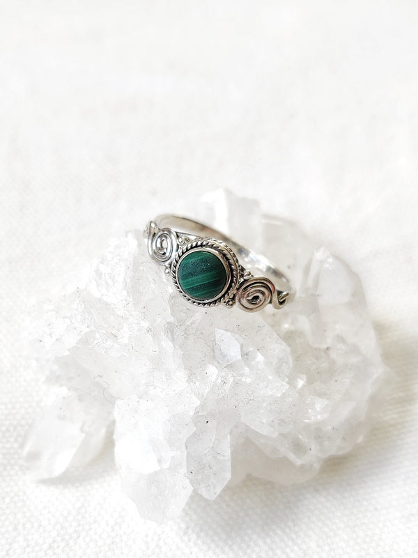This is a sterling silver ring with a spiral design and malachite crystal gemstone that is striped green in colour, sitting on top of a clear quartz crystal, both available at our third eye crystal store in Auckland New Zealand